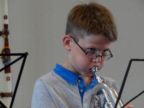 Een jonge muzikant speelt bugel achter de lessenaar.